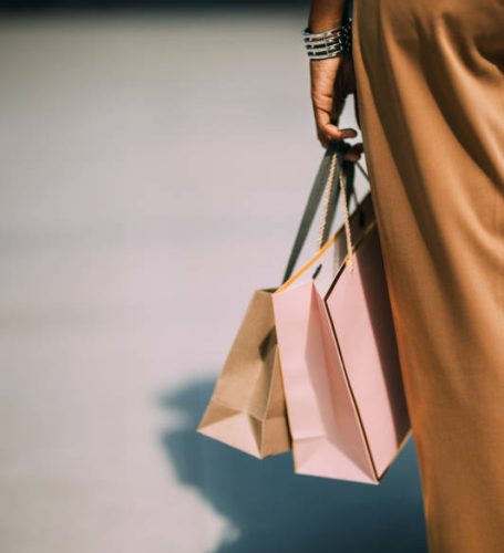 A back view of an unrecognizable Latin female with shopping bags standing on the street after being at the shopping mall.