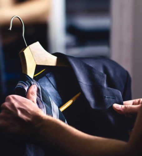 Man getting ready and dressing up in a suit. Luxury jacket and tie in hanger. Trying on outfit before date or wedding. Fitting room in mall store, closet or tailor shop. Formal businessman fashion.